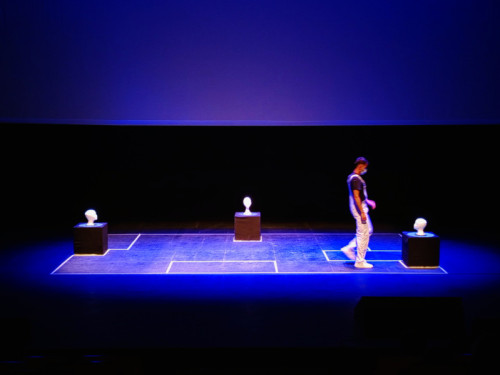 Escena de la obra de teatro "Bienestar por suscripción", en la que aparece un actor en el escenario caminando