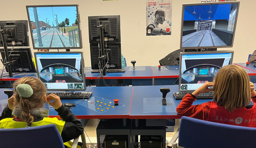 Niño y niña utilizando el pupitre del simulador de conducción de metro ligero