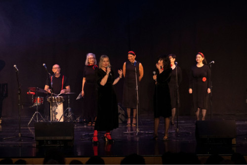 Grupo de jazz vestido de negro y rojo sobre un escenario, compuesto por seis mujeres y un hombre